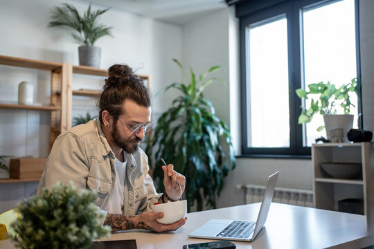 Freelancer eating breakfast and working from home office