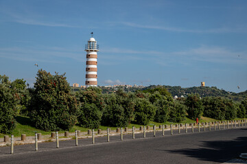 The striped Belem Lighthouse stands tall near Lisbon, Portugal, under clear blue skies on a quiet summer afternoon, guiding vessels navigating the Tagus River's entrance.