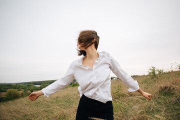 Young woman enjoying freedom in nature with open arms and hair blowing in wind