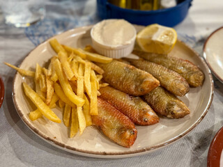 Traditional Greek Dish Fried Rouzetia Fish with French Freis and Lemon in Greek Tavern on Rhodes island