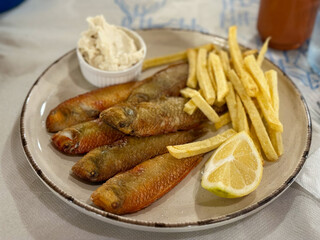Traditional Greek Dish Fried Rouzetia Fish with French Freis and Lemon in Greek Tavern on Rhodes island