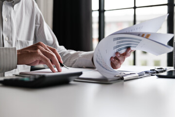 Corporate analyst sitting at desk with audit papers, financial ledger and calculator in business...