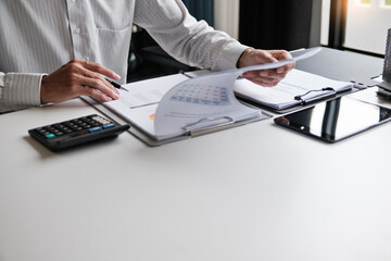Corporate analyst sitting at desk with audit papers, financial ledger and calculator in business...