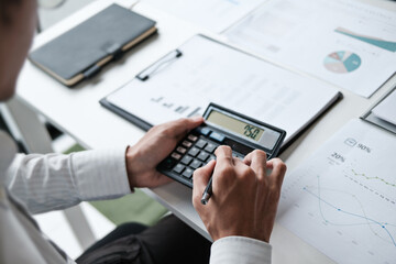 Office administrator reviewing audit documents on table with calculator and financial file folders