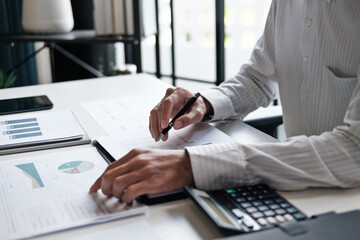 Administrative staff reviewing company budget report with calculator, document stack and focus at...
