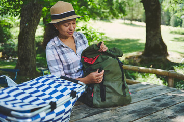 Woman Preparing Backpack at Picnic Table in Scenic Forest Area