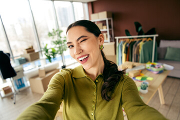 Smiling young entrepreneur in a stylish workspace showcasing her fashion designs and textiles