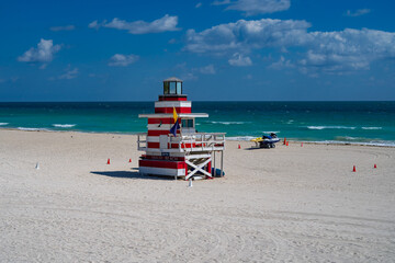 Obraz premium Miami Beach lifeguard at the summer beach. South Miami Beach with lifeguard. Sky above lifeguard tower in Miami. Iconic lifeguard tower on sand in Miami. A symbol of Miamis coast.