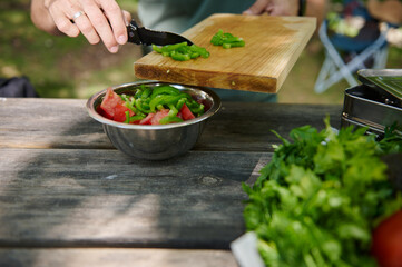 Preparing a Fresh Vegetable Salad Outdoors on a Picnic Table Surrounded by Greens