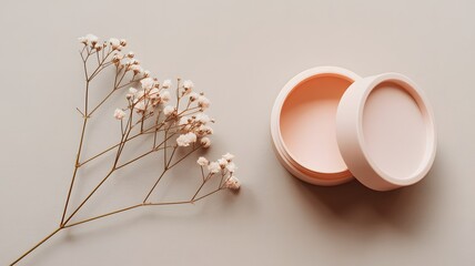 Minimalist flat lay with dried flowers and open pink container on neutral background, symbolizing beauty, simplicity, and natural elegance