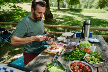 Man Preparing Outdoor Tacos Amidst Nature With Fresh Ingredients on Wooden Table