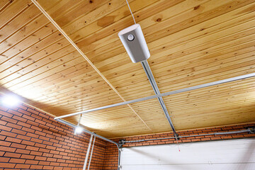 garage interior with a wooden plank ceiling, brick wall, and a garage door opener attached to the...