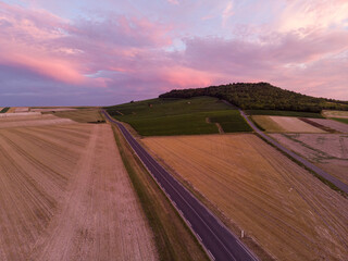 Aerial view of  a road through the rolling hills with vineyards of the Champagne region at pink sunset