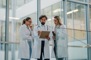 Medical team meeting discussing patient records in hospital corridor