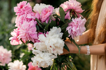 girl holding pink flowers peonies in the  garden