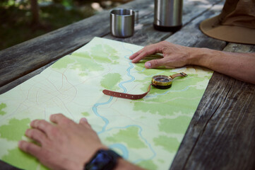 Hands Examining a Topographic Map on a Wooden Table Outdoors