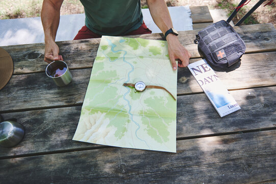 Hiker Planning a Route Using a Map and Compass Outdoors - Powered by Adobe