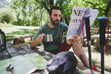 Man Enjoying Morning Outdoors While Reading Newspaper in Scenic Park
