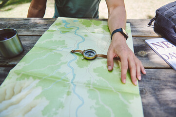 Explorer Planning Path using Map, Compass, Resting at Outdoors Table