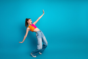 Dynamic young woman in casual style creatively posing against a bright blue background, expressing...