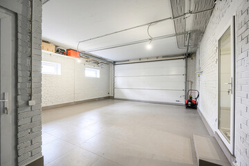 Clean, bright garage with white brick walls, tiled floor, closed white garage door, and visible wiring