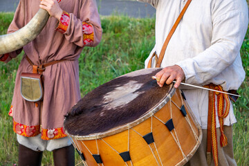 people in historical costumes, one playing a drum and another holding a signal horn. Scene from a...