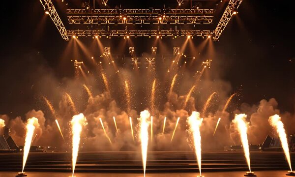 Stage fireworks display, pyrotechnics bursting, lit by overhead lights, creating dramatic entertainment scene