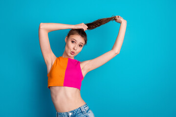 Fototapeta premium Bright young woman posing with playful expression against vivid blue backdrop, showcasing cheerful energy and fashionable attire.