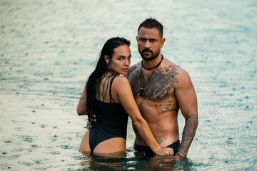 Couple in love embracing each other in water. Romantic couple kissing in the sea. Sexy couple hug on the summer beach. Love and romance couple. Muscular Hispanic man and woman in love.