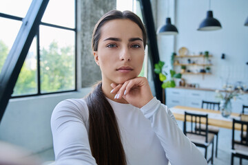 Close-up selfie portrait of teenage female looking at web camera