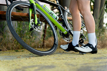 Professional cyclist wearing cycling shoes standing next to her bike