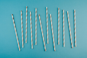 Rose gold striped paper straws on blue background for birthday party or event concept