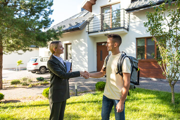Real estate agent shaking hands with a new client and both looking contented