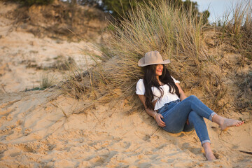 Young, pretty woman, black hair, wearing white shirt, jeans and hat, smiling and happy, looking...