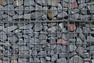 Rubble stone in galvanized mesh. Background. Gabion mattress made of woven mesh with stones for creating walls. Stones in mesh, creating decorative walls, strengthening