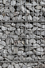 Rubble stone in galvanized mesh. Background. Gabion mattress made of woven mesh with stones for creating walls. Stones in mesh, creating decorative walls, strengthening