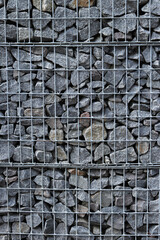 Rubble stone in galvanized mesh. Background. Gabion mattress made of woven mesh with stones for creating walls. Stones in mesh, creating decorative walls, strengthening