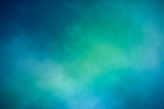 Abstract soft focus background with a gradient of deep blue and vibrant teal green colors creating a dreamy ethereal atmosphere