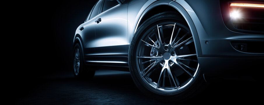 Shiny alloy wheel of a luxury car with soft lighting, silver, dark blue background