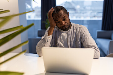 African american man at the laptop looking tired and suffering from a headache