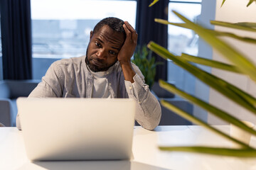 African american man at the laptop looking tired and suffering from a headache