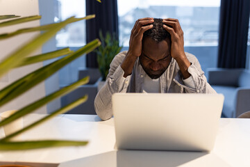 African american man at the laptop looking tired and suffering from a headache