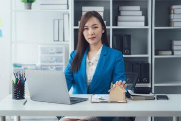 Confident Businesswoman at Desk: A portrait of a young Asian businesswoman exudes confidence and...