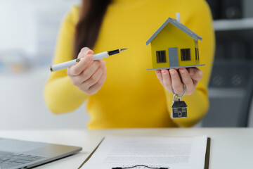 Home Ownership Vision: A professional presents a miniature house, keys, and a pen, symbolizing home...