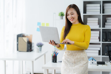 Content Asian Office Worker: A charming Asian woman, bathed in the soft glow of natural light, is captured mid-action as she engages in a seamless workflow.