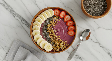 A vibrant smoothie bowl garnished with banana slices, strawberries, granola, and chia seeds.