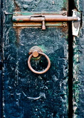 Close-up of an old door with a latch and ring handle.