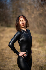 Girl in a field wearing a leather jumpsuit. Catsuit
