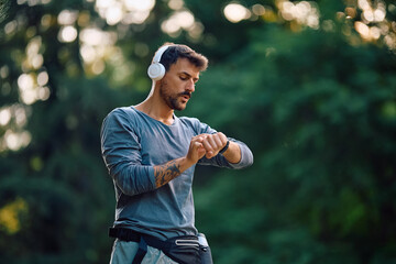 Male runner using fitness tracker while exercising in nature.