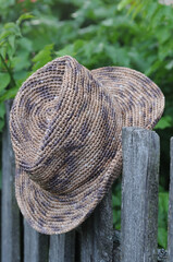 Straw hat on a wooden fence in the garden, close up